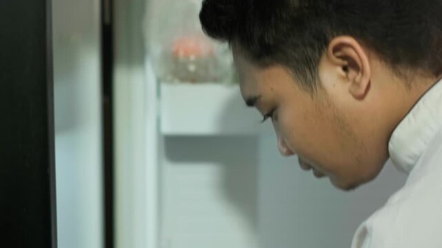 Young Southeast Asian chef taking spring onion from refrigerator