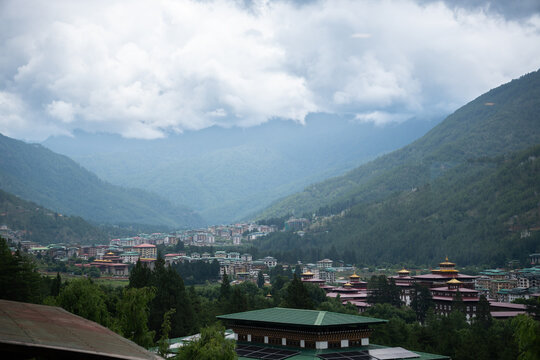 Scenic cityscape view of Thimphu valley and traditional Bhutanese architecture surrounded by lush green Himalayan mountains under an overcast sky in Bhutan