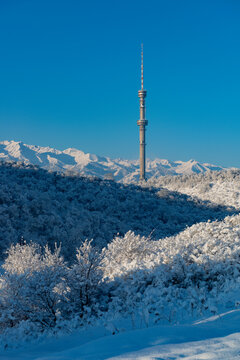 Snow-covered hills and mountains with the famous TV tower on Kok Tobe Hill in the Kazakh city of Almaty on a winter morning.