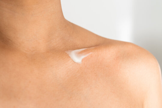 A woman unrecognizable with moisturizer on her collarbone. Skincare