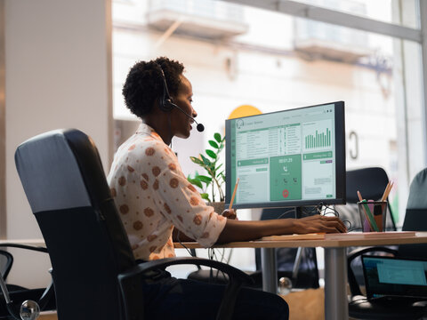 Customer care worker is talking to client at office via headset 