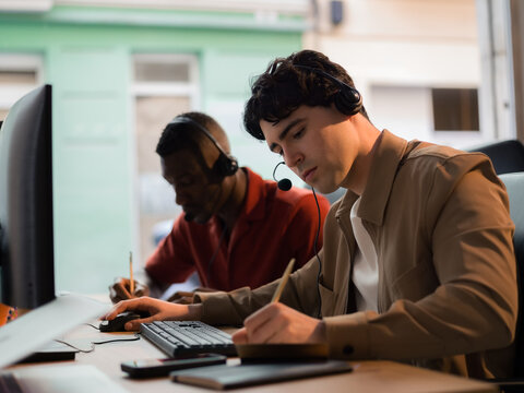 Focused call center workers writing notes 