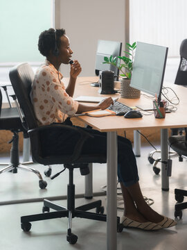 Woman talking to customer via headset in call center office 