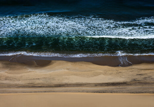 Aerial top down view of desert dunes meeting the Atlantic ocean at Sandwich Harbour, Namib desert, Namibia