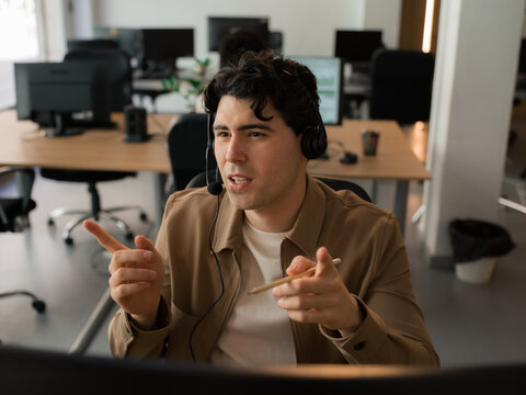 Man Speaks on Headset While Sitting in Office at Daytime