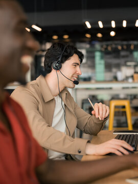 Positive men working at call center with clients 