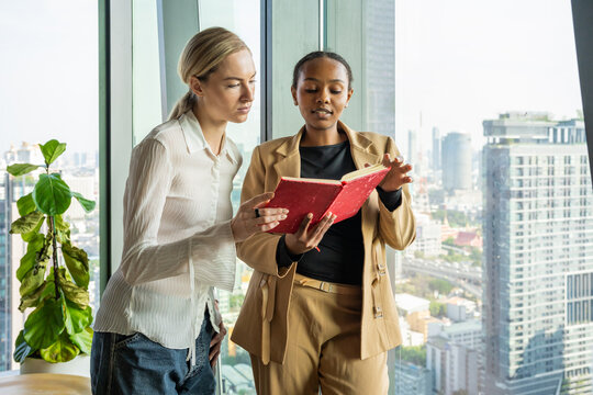 Two Women Discuss Work in a Modern Office With a City View