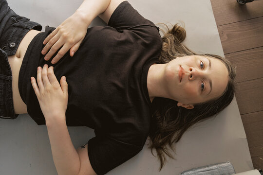 Girl lying on a mat in a simple indoor space during the day