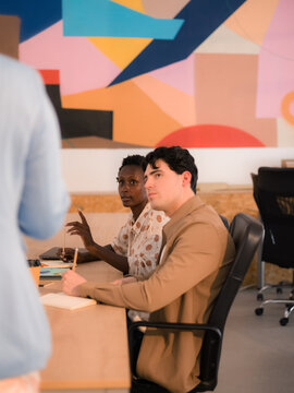Listeners talking to speaker during business meeting at office 