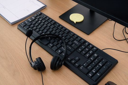 Headset and keyboard on wooden desk at office 