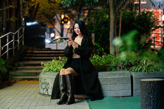Woman using smartphone at night in Tokyo