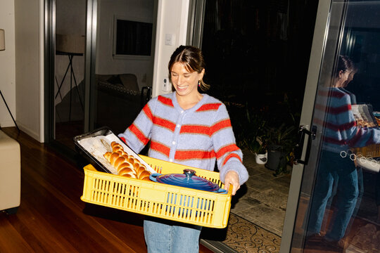 Smiling private chef carrying catering basket into home dinner UGC