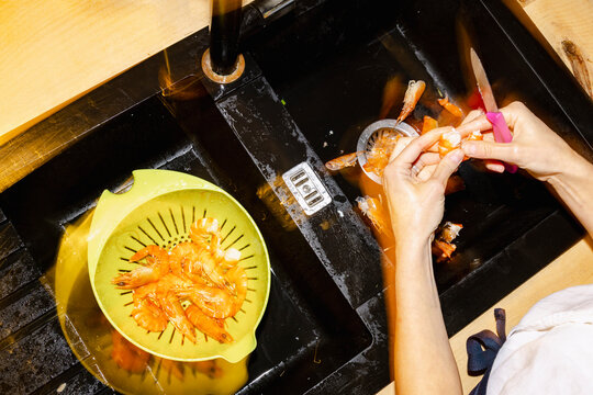 Long exposure hands peeling prawns for home seafood dinner