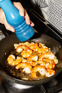 Seasoning prawns in frying pan for homemade seafood dinner