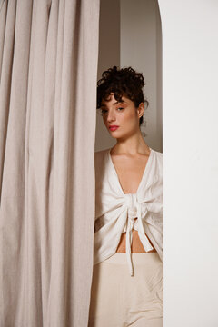 Model Poses Near Curtain in Indoor Setting During Daylight Hours