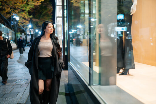 Japanese woman window shopping in Tokyo at night