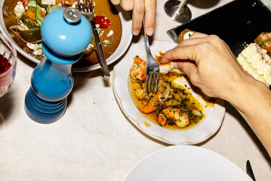 One person eating prawns while another dips bread in sauce