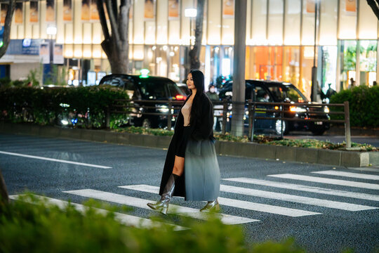 Japanese woman crossing Tokyo street at night