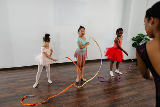 Girls learning rhythmic gymnastics ribbon dancing in studio