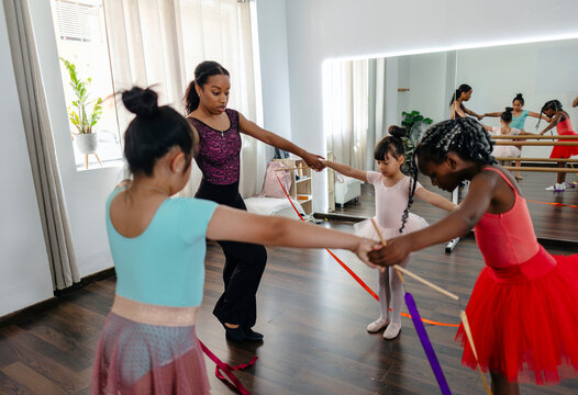 Female teacher leading diverse girls in a creative dance class