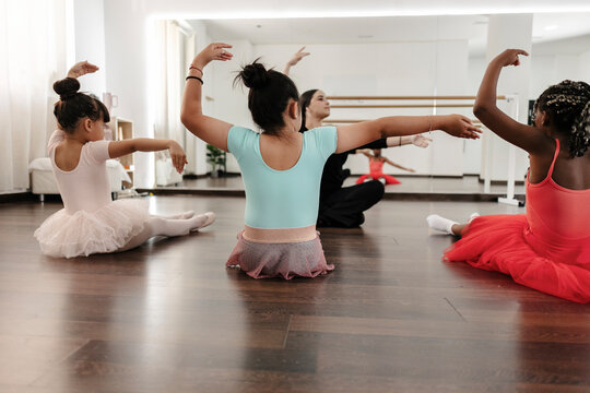 Young diverse girls learning ballet with instructor in studio
