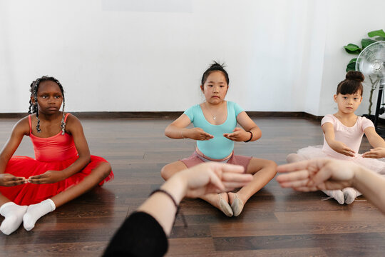 Diverse young girls learning ballet hand positions during class