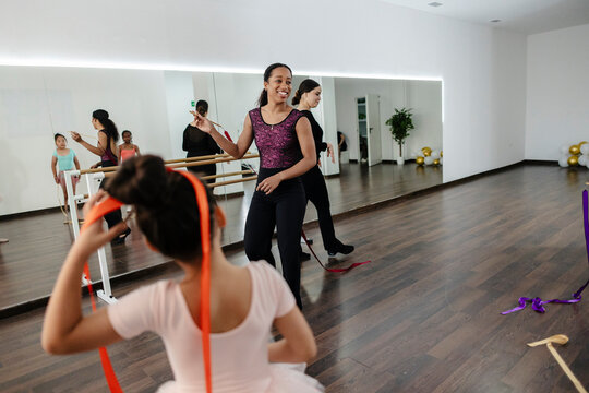 Dance instructor teaching young girls rhythmic gymnastics class