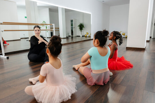 Ballet teacher instructing diverse young students in studio