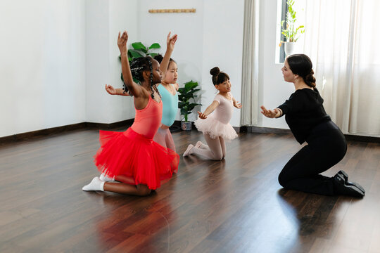 Teacher guiding diverse children learning ballet steps