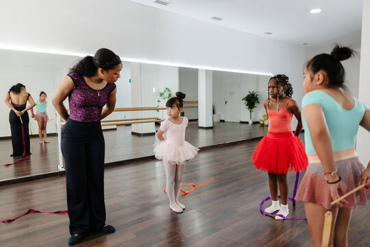 Diverse young girls learning rhythmic gymnastics with teacher