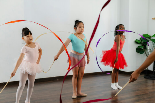 Diverse young girls practicing rhythmic gymnastics with ribbons
