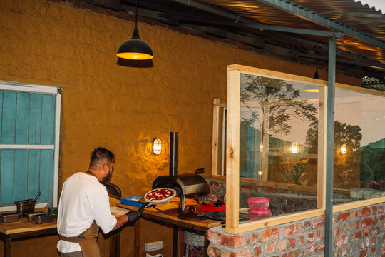 Chef Prepares Pizza in Outdoor Kitchen in the Evening