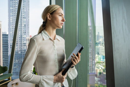 Business Woman Looks out the Window in City Office Building