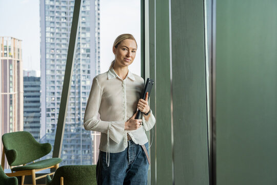 Woman Standing by Window in Modern Office With City View