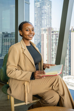 Businesswoman Seated Holding Notebook in Modern Office Setting