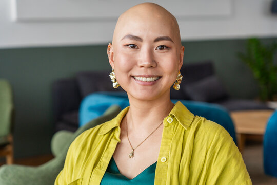 Woman With Bald Head Smiles in a Casual Setting With Colorful Chairs