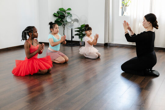 Ballet teacher guiding young diverse students during lesson