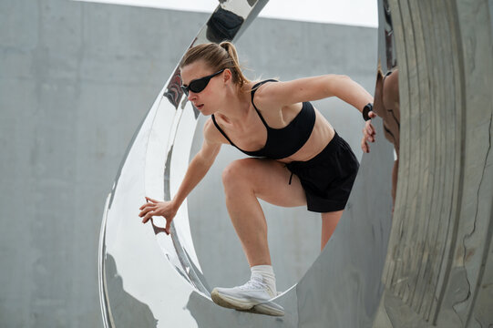 Sporty woman standing inside modern sculptural composition