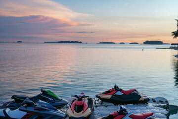 Colorful tropical sunset over calm ocean with several personal watercraft docked at a floating marina in an island resort. © Livia