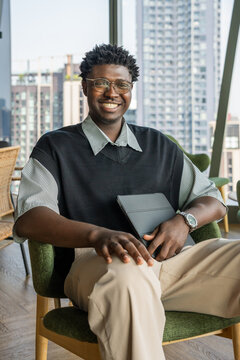 Happy Man Sitting in a Chair With a Tablet in a Modern Office Space