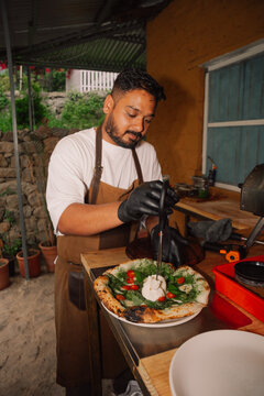 Chef Prepares Pizza With Fresh Ingredients in Outdoor Kitchen