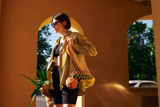 Woman holding a mesh bag of groceries 