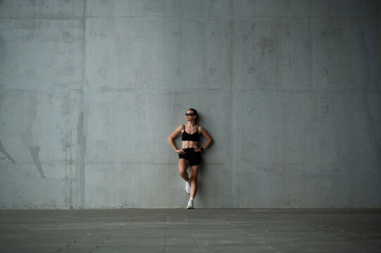 Athletic woman standing outdoors near concrete walls
