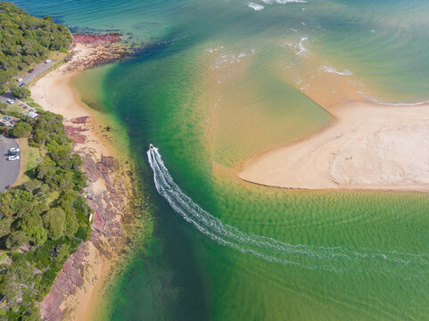 Pleasure boat leaving a wake through a channel leading out the ocean
