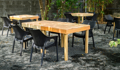Fototapeta premium Outdoor dining area with wooden tables and black chairs in a peaceful garden setting