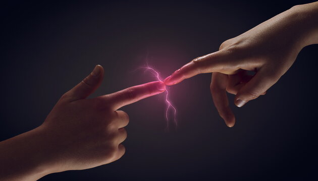 Two hands reaching together with energy flash on black background 黒背景で二つの手が繋がりエネルギーの閃光が走る瞬間