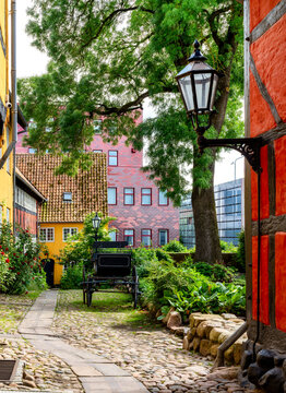 Historic Borgerhaven courtyard with half timbered houses, cobblestone pavement, antique horse carriage, mature tree and landscaped garden in Kolding, Denmark