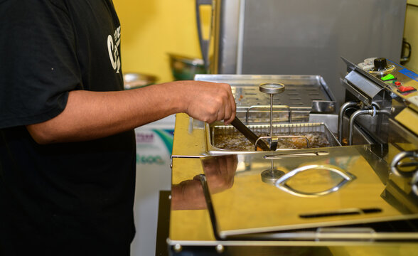 Chef deep-frying fried chicken in a commercial kitchen, close-up.