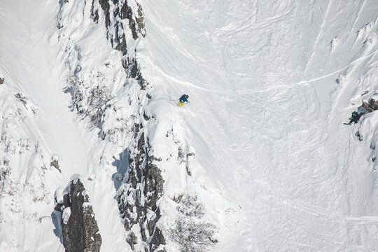Extreme freeride skier dropping from a steep rocky ridge in a high 
