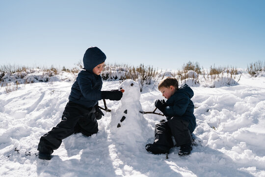 Children building snowman enjoying fun winter activity